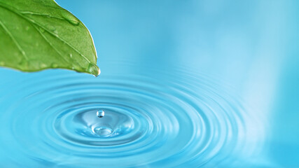 Naklejka na ściany i meble Blue water drop with green leaf, macro shot