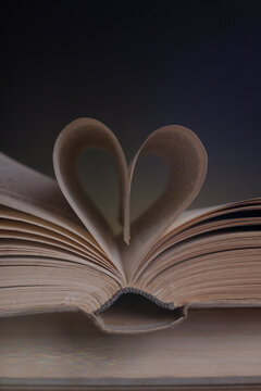 An old book. The heart is depicted by the pages of a book. Dark background.