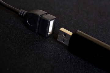 A black USB device, a flash drive or card reader and an OTG adapter are on a dark background....