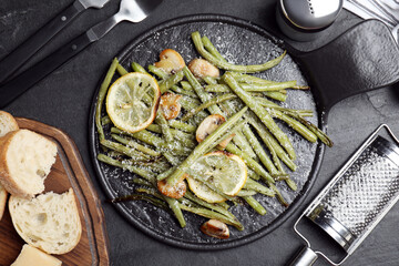 Delicious baked green beans served on black table, flat lay