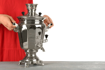 Woman holding traditional Russian samovar on grey table against white background, closeup. Space for text