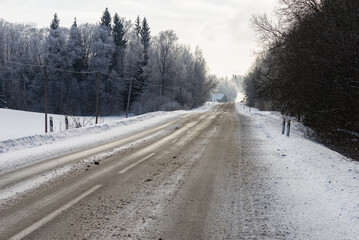 Fototapeta premium Winter road in snowy forest on a cold day.