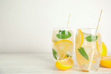 Cool freshly made lemonade in glasses on white wooden table. Space for text