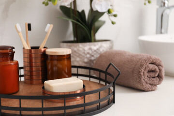 Tray with different toiletries and towel on countertop in bathroom, closeup