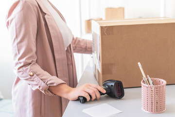 Woman employee of transport company scanning parcel using barcode scanner to confirm sending...