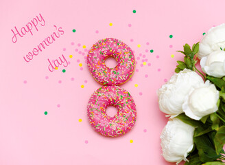 A greeting card for women's day with donuts in the form of the number eight lying on a pink background, covered with pink icing and colorful beads and white flowers.