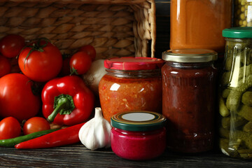 Jars with different canned food on wooden background