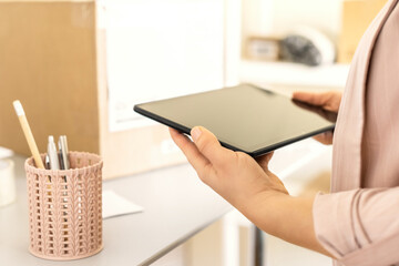 Female owner of start up small business using mobile app on tablet checking parcel box. Warehouse...