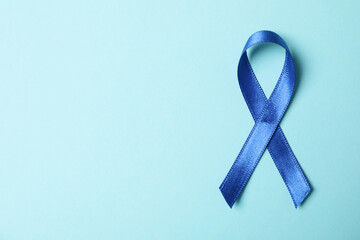 Blue awareness ribbon on light blue background, space for text