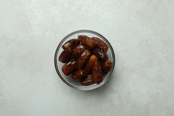 Glass bowl of dates on white textured background