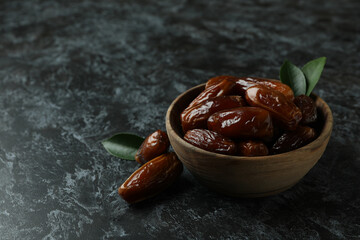 Wooden bowl of dates on black smokey background