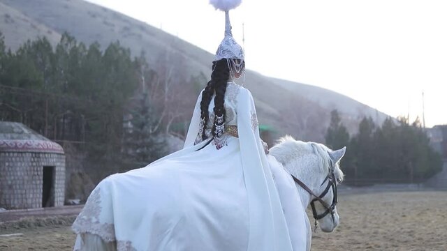 An Asian girl in a national costume is riding a horse. Kyrgyz national costume.
