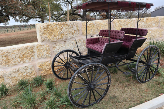 Shot of an old horse carriage phaeton in red and black colors in the background of a beige wall