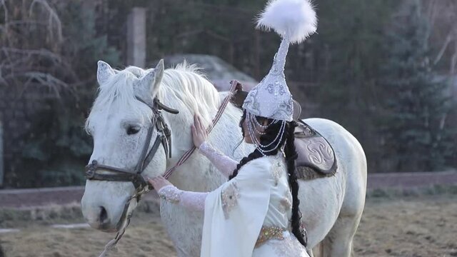 An Asian girl in a national costume is riding a horse. Kyrgyz national costume.