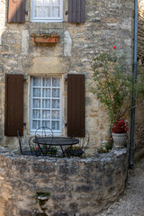Fototapeta na wymiar A black metal table and chairs on the romantic terrace of an old stone house in Beynac-et-Cazenac, France