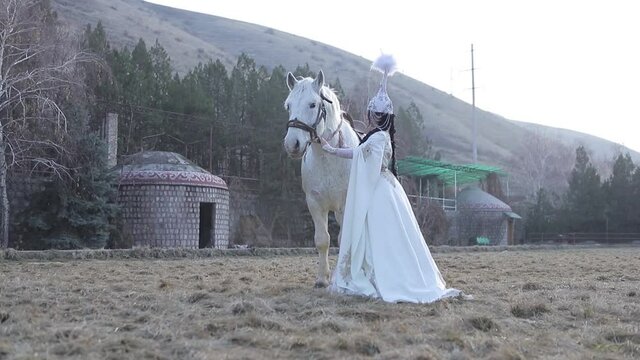 An Asian girl in a national costume is riding a horse. Kyrgyz national costume.