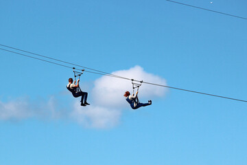 Man and woman descend on a zipline