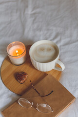 Breakfast in bed. Coffee mug, heart-shaped cookies, book, glasses, candle, wooden tray. Women's Day. Cozy.
