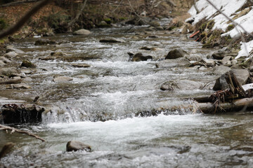 Details with the clear water of a running mountain stream during a cold and sunny winter day in the Romanian Carpathian Mountains.
