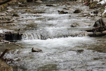 Details with the clear water of a running mountain stream during a cold and sunny winter day in the Romanian Carpathian Mountains.