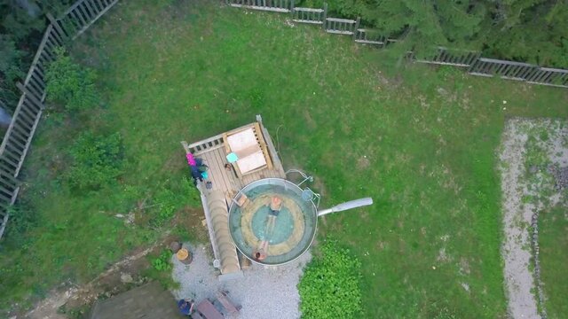Couple Enjoying Hot Tub At Hija Glamping Lake Bloke. Aerial Pedestal Up, Top Down View