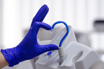 Saliva ejector and a hand in a disposable glove symbolize love in dentistry.Hand in a blue...