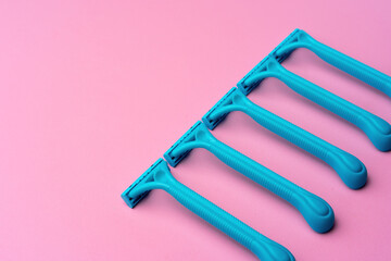 Female disposable razors on pink background top view