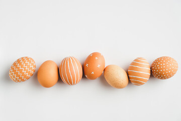 Painted Easter eggs in row on white background. Flat lay, top view. Elegant, simple, modern style.