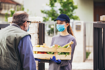 Teenage girl is delivering some groceries to an elderly person, during the epidemic coronovirus,...