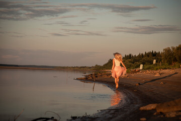 blonde girl on the riverbank at sunset, selective focus