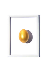 Top view of golden yellow colored egg and its shadow in frame isolated over white background. Easter celebration concept. Creative greetings. 
