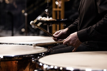 Hands of a musician playing the timpani in the orchestra close up