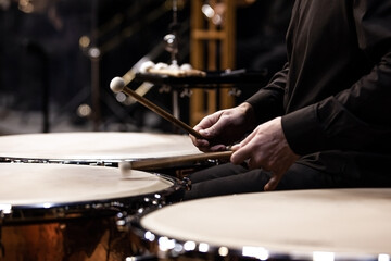 Hands of a musician playing the timpani in the orchestra close up