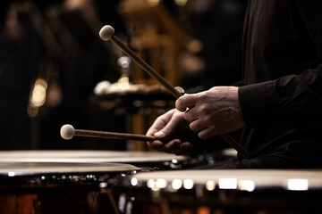 Hands of a musician playing the timpani in the orchestra close up