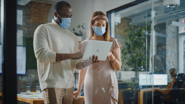 CEO and Chief Executive Wearing Face Masks Talking About Company Business Growth, Analyze Data, Use Laptop Computer. Two Professionals Discussing Revenue Increase, Market Disruption, Planning Strategy