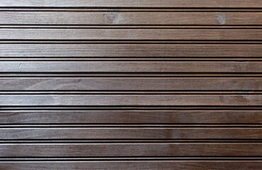 dark wood surface formed by narrow boards in horizontal position. side light enters. background for invitations or cards for events such as weddings.