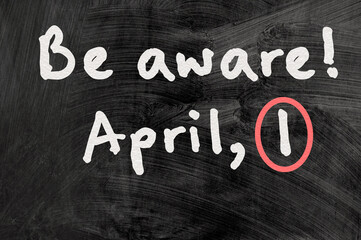 be aware on blackboard note over a dark background. april fools day