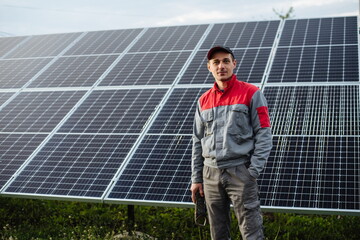 Portrait of an electrician engineer, on a background of solar panels. The future of alternative energy and sustainable energy.
