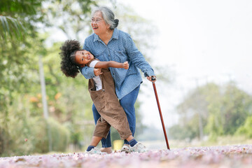 Multicultural family Afro grandchild with Asia grandmother playing in the park ,leisure activity...