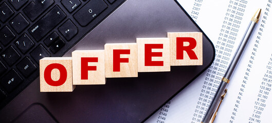 On the laptop, on wooden cubes near the pen, the word OFFER is written.