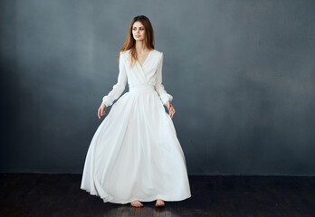 Fototapeta na wymiar Woman on a gray background in a white dress dance model in full growth