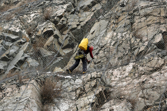 Worker climbs the safety net near the aftermath of a stone landslide at the eighth kilometer of Struma Motorway. - Powered by Adobe