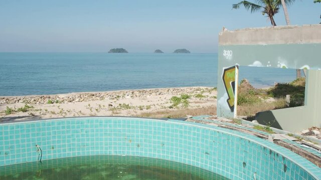 tilt up shot of a empty swimming pool at a abandoned beach bungalow resort on Koh Chang island in Thailand