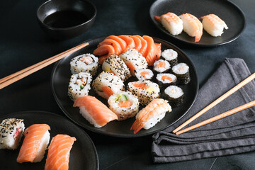 Lunch or dinner at a Japanese restaurant. Set  sushi maki rolls  with salmon, avocado, cream cheese. Sushi menu. Japanese food. Black background. Top view. Food delivery coronavirus