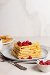 Stack golden pancakes or crepes with raspberries in a grey plate. Breakfast concept. Maslenitsa. Mardi gras