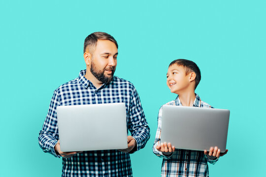 Family - Child And A Man In Identical Plaid Shirts Smiling And Holding Gray Laptops Together Isolated Over Colored Background  