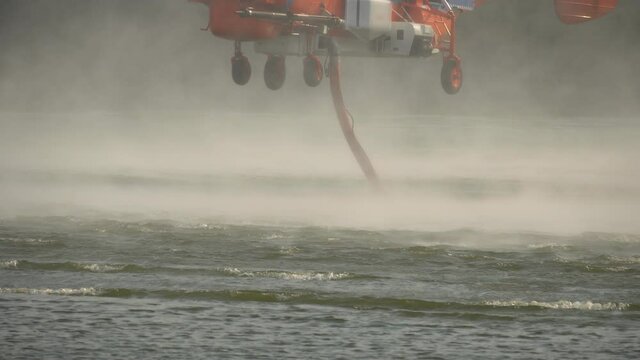 Firefighting helicopter is hovering over the lake to refills water