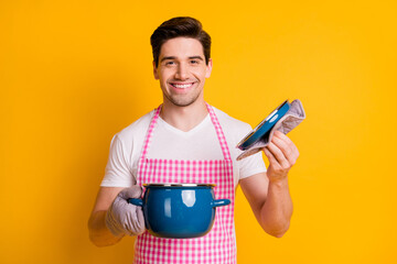 Photo portrait of man in kitchen gloves opening pot holding lid isolated on vivid yellow colored...