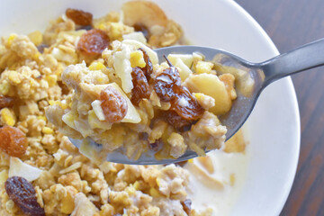 Muesli fruit and fiber cereal with dry oat, corn, banana, raisin, and apple with milk.