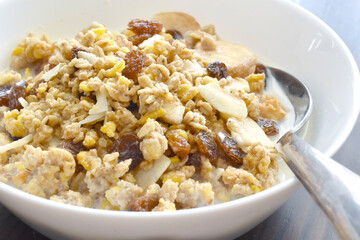Muesli fruit and fiber cereal with dry oat, corn, banana, raisin, and apple with milk.